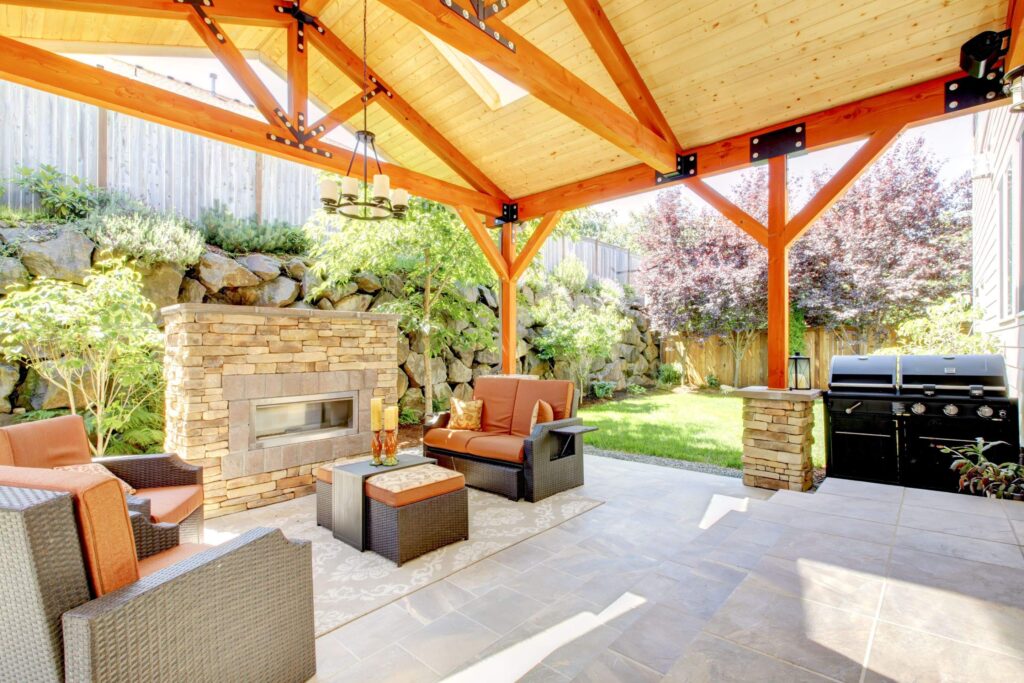 Exterior covered patio with fireplace and furniture. Wood ceiling with skylights. - ProNail Outdoor Living